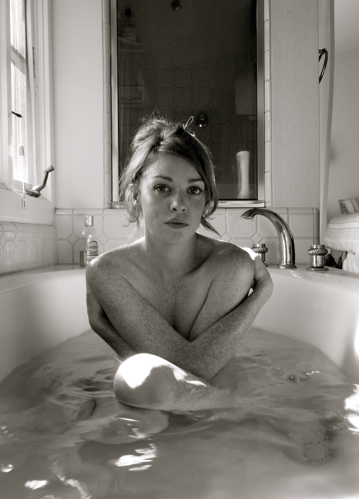 Обнаженная темноволосая девчонка с камерой в ванной