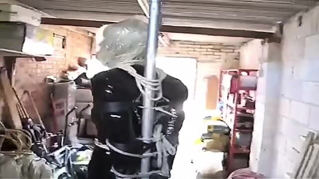 PatsyPVC Shiny Tight PVC Skirt Sissy Tranny Slut in rope and chain bondage with large Ballgagged and Anal buttplug with Shiny Black Seamed Stockings and High Heels Stored in Garage