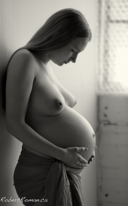 Tenderly cradling her stomach in black and white