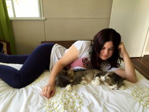 amateurfoto beautiful brunette in leggings with the perfect figure laying next to her cat.