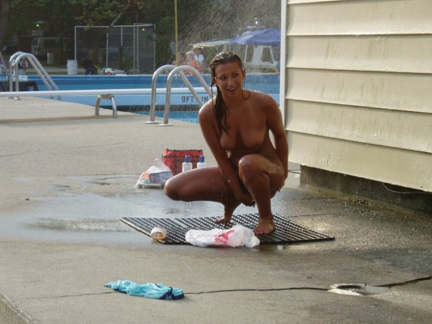 Lovely naked girl is looking a bit awkward at the public swimming pool