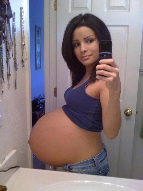 Selphy pregnant girl with an outstretched belly in front of the mirror. 