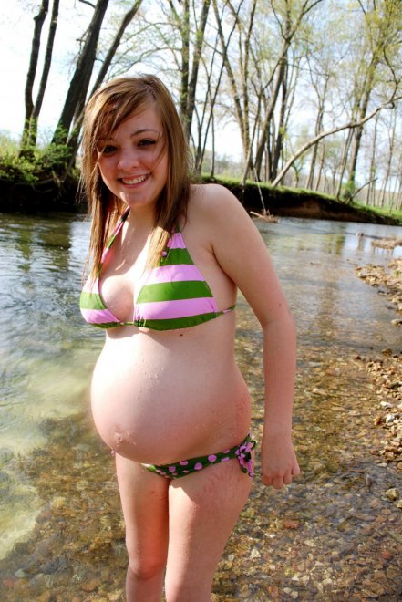 Pregnant girl in a swimsuit on the river