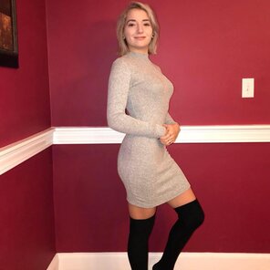 Blonde pixie wearing black thigh-highs, posing in a form fitting dress